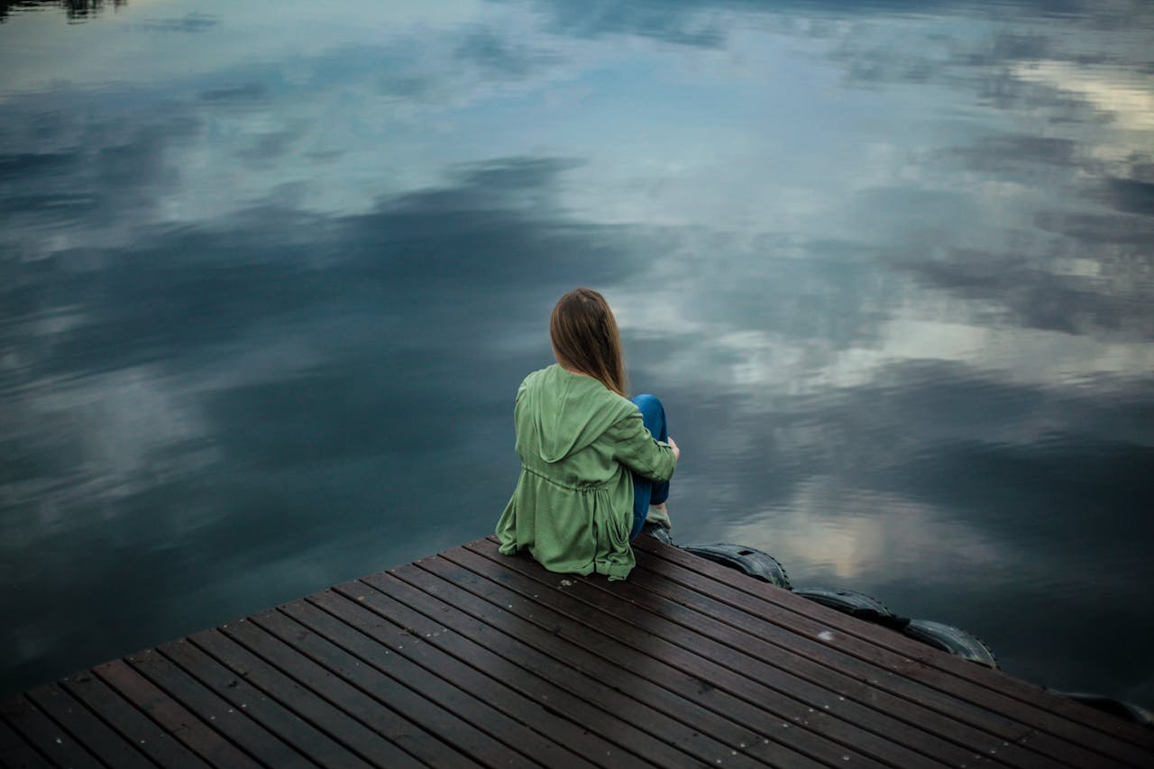 Photo of person sitting alone on a jetty by Keenan Constance